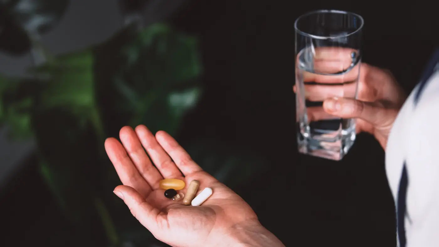 Hand met Resveratrol erop naast glas water