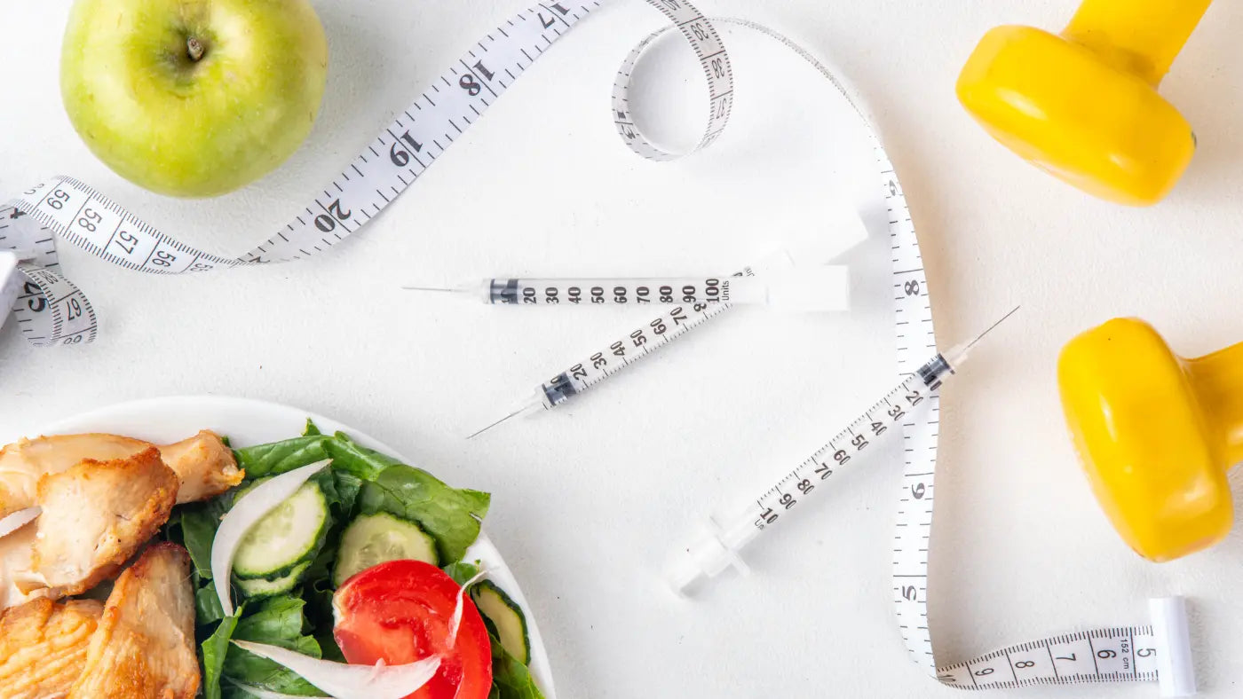 een opstelling met gezondheids- en fitnessthema, met spuiten, een groene appel, een frisse salade met kip, een wit meetlint